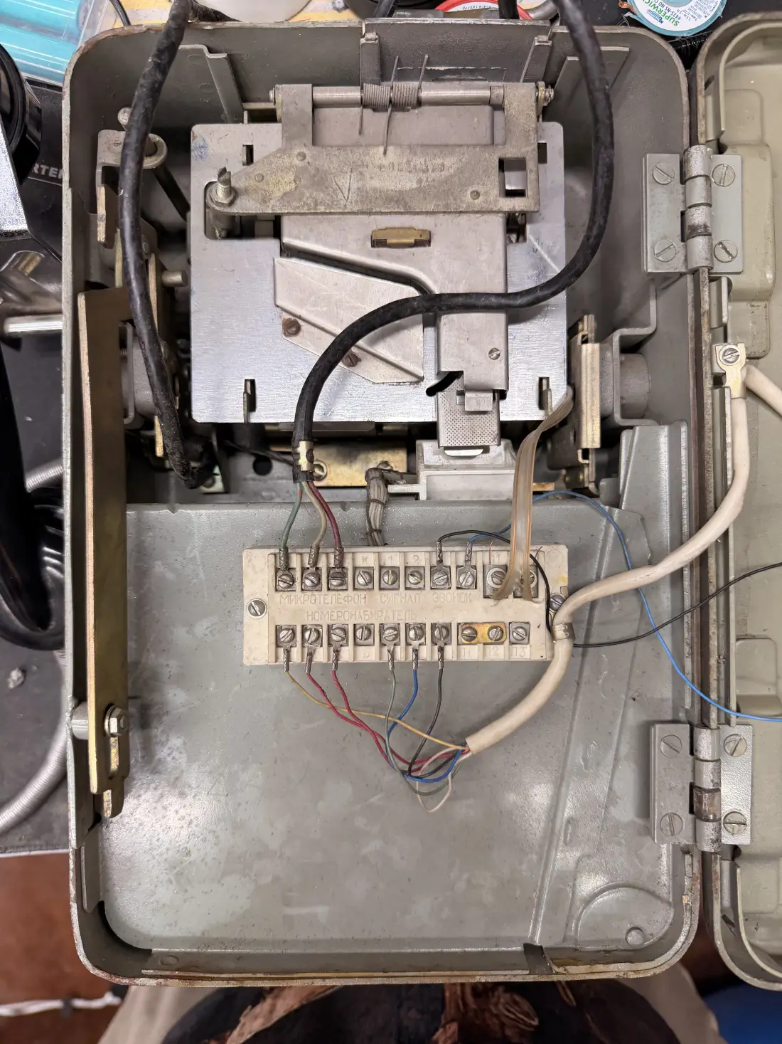 The inside of the payphone, showing the original coin mechanism and a terminal block of coloured wiring.
