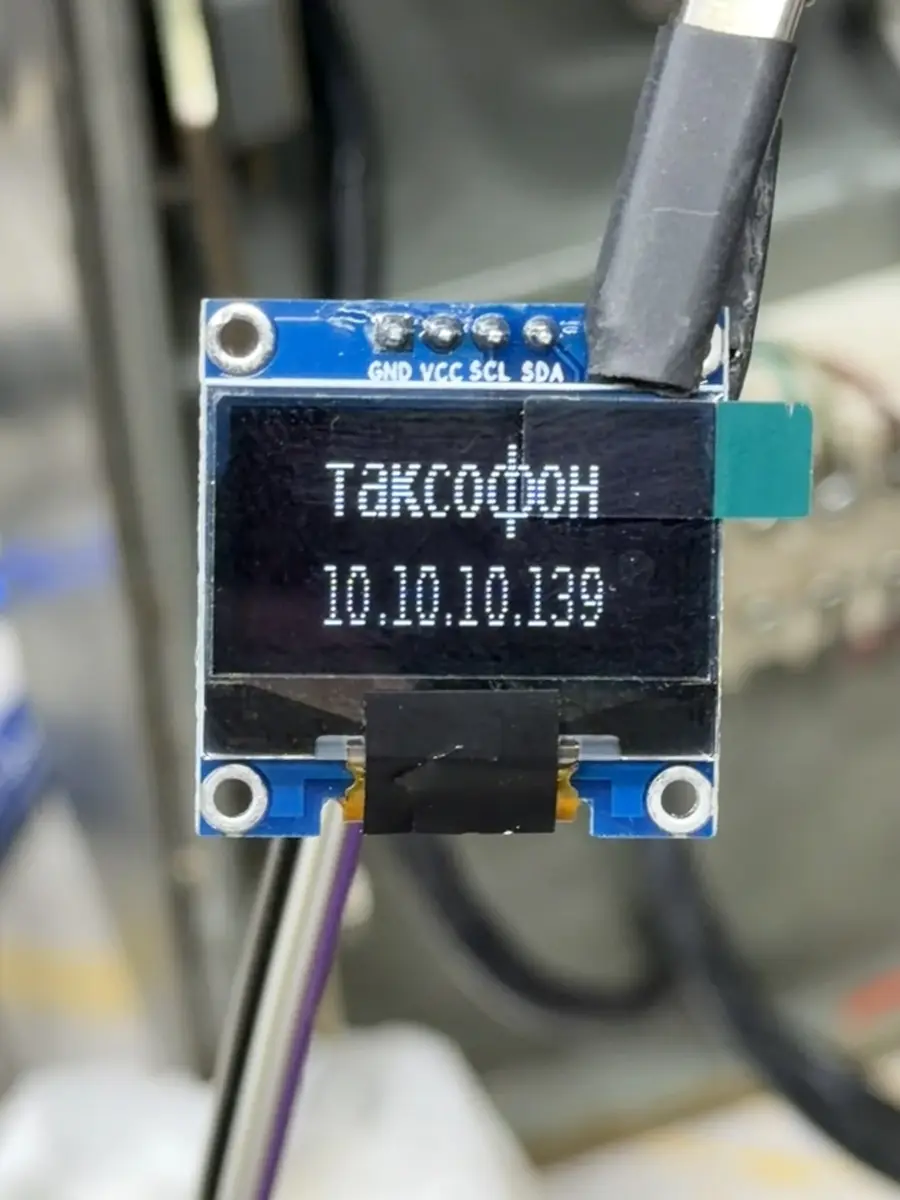 A small OLED display wired into the phone reading таксофон above an IP address.