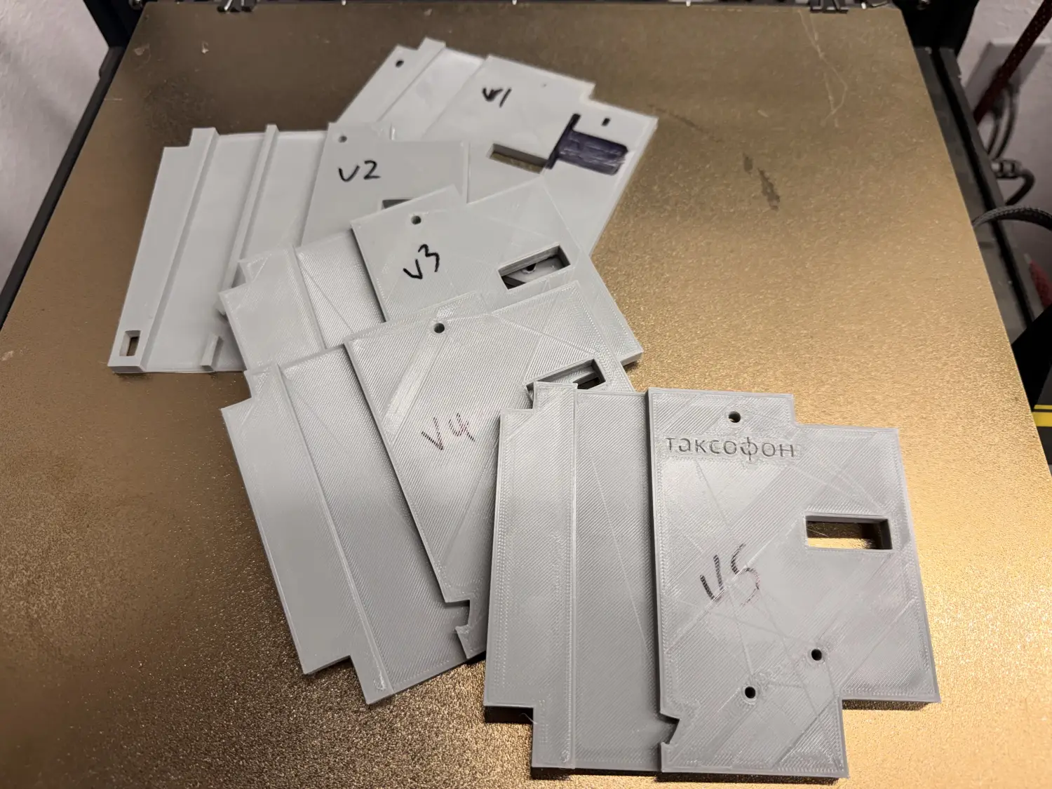 A pile of failed 3D-printed coin mechanism parts, each labelled v1 through v5.
